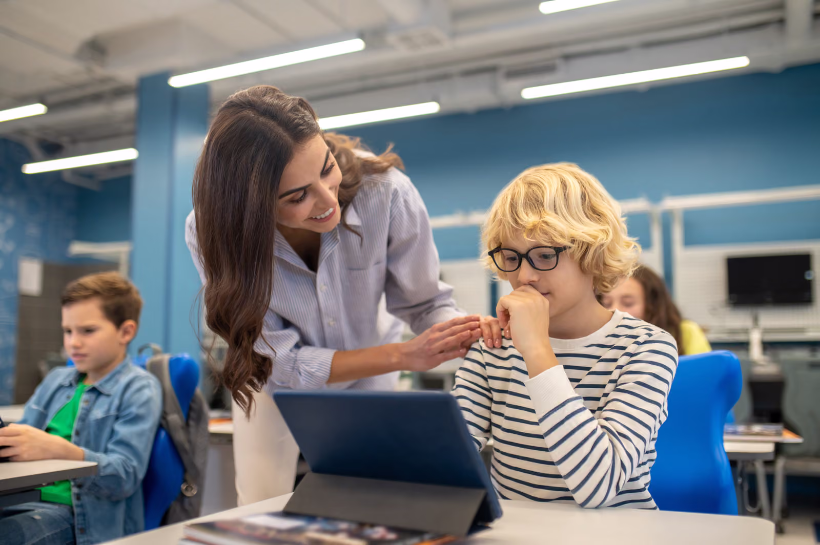 A teacher helping a student with a tablet